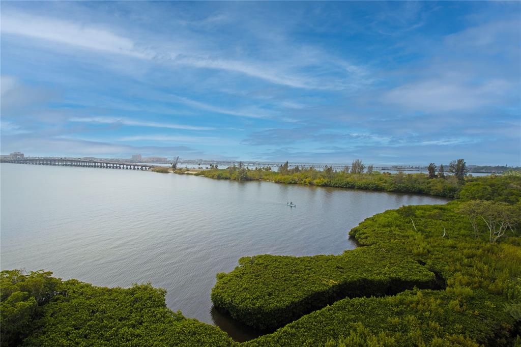 An aerial view shows a body of water, a long bridge, and dense green mangroves — 615 RIVIERA DUNES WAY UNIT 402, PALMETTO, FL
