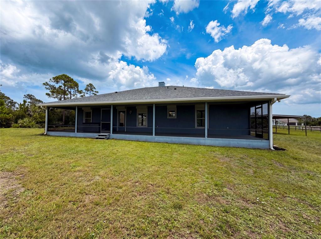 A single-story house with a dark exterior and a wrap-around screened porch — 2620 KELLY LANE, MALABAR, FL
