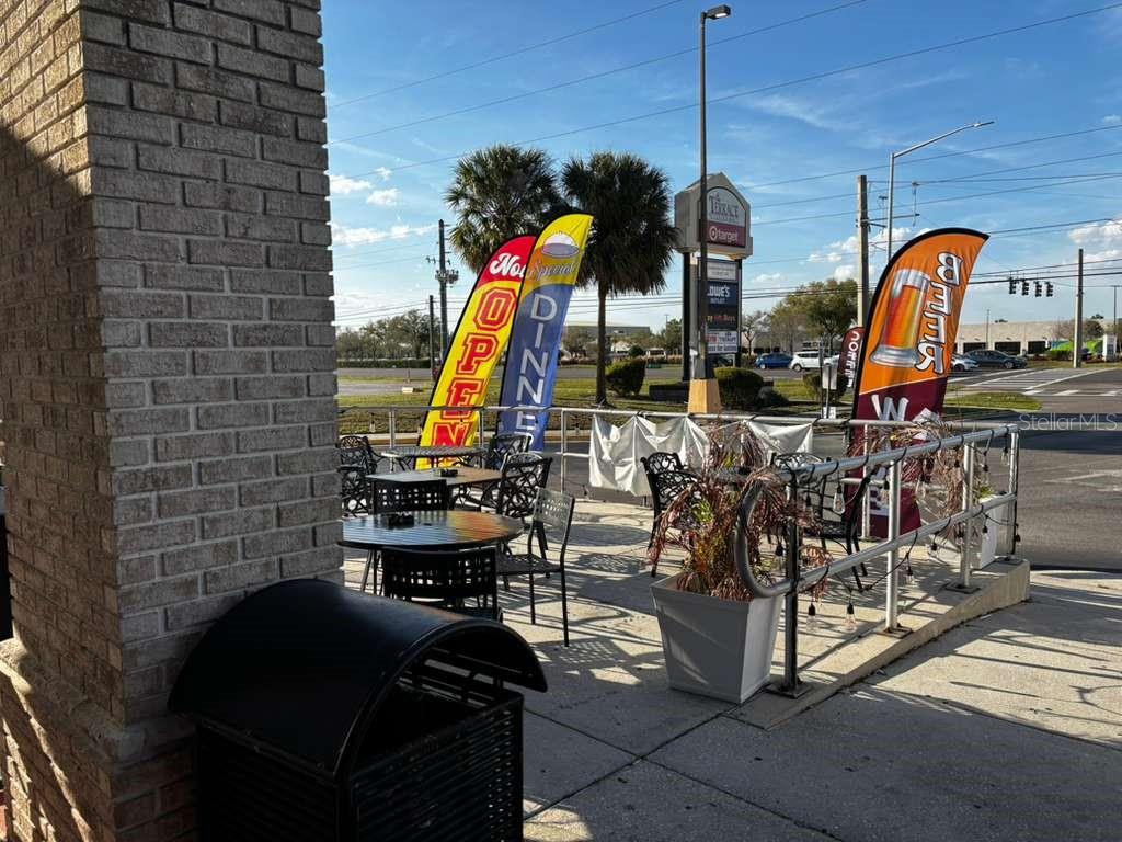 An outdoor patio area features metal tables and chairs next to a brick building wall — 730 SAND LAKE ROAD UNIT 30, ORLANDO, FL