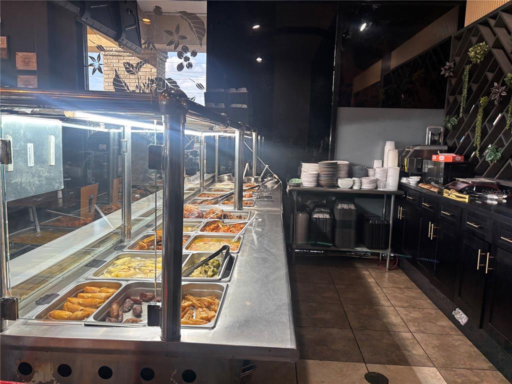 A commercial buffet line features stainless steel food warmers and a stack of white plates — 730 SAND LAKE ROAD UNIT 30, ORLANDO, FL