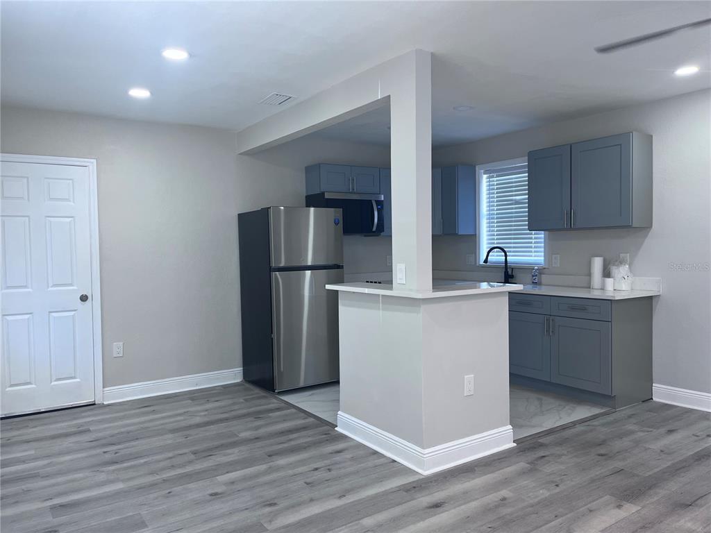 A kitchen features gray cabinets, stainless steel appliances, and light gray wood-look flooring — 3215 W PINE STREET, TAMPA, FL