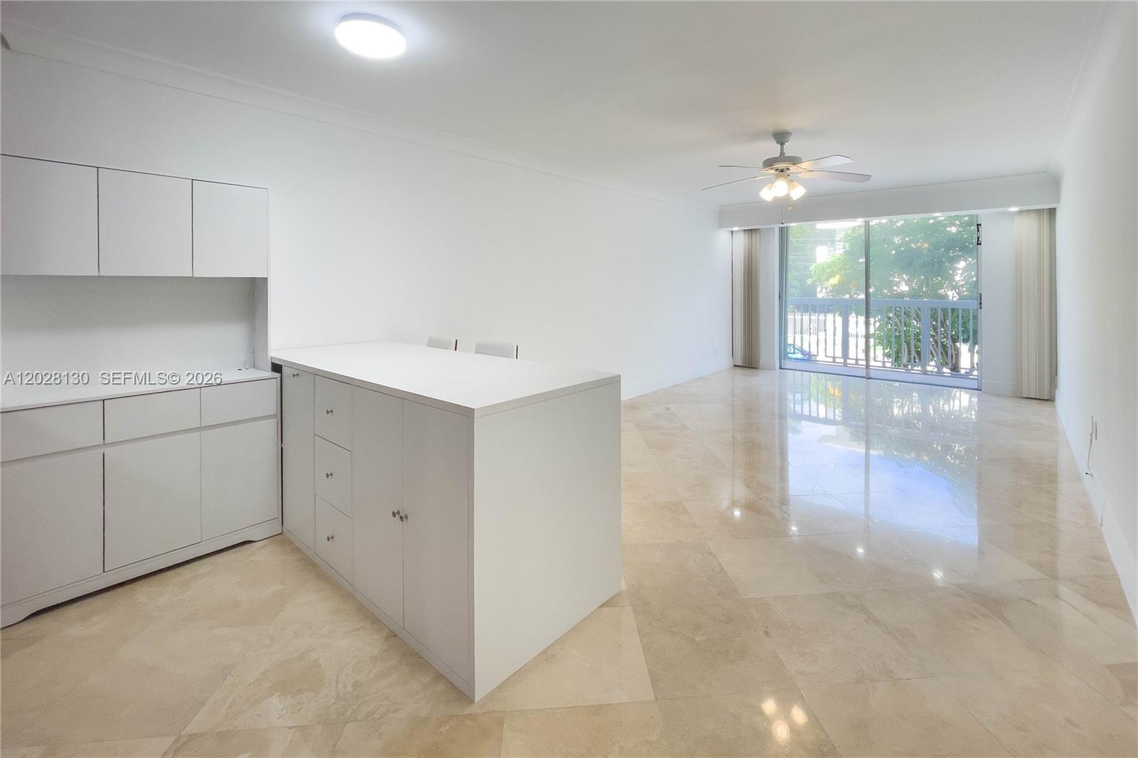 A white kitchen island and cabinetry sit in a living area with marble floors — 1670 Bay Rd # 2D, Miami Beach FL 33139, MIAMI BEACH, FL
