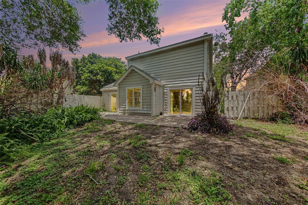 The exterior of a two-story house features light-colored siding, a small patio, and a backyard — 2758 WAYMEYER DR, ORLANDO, FL