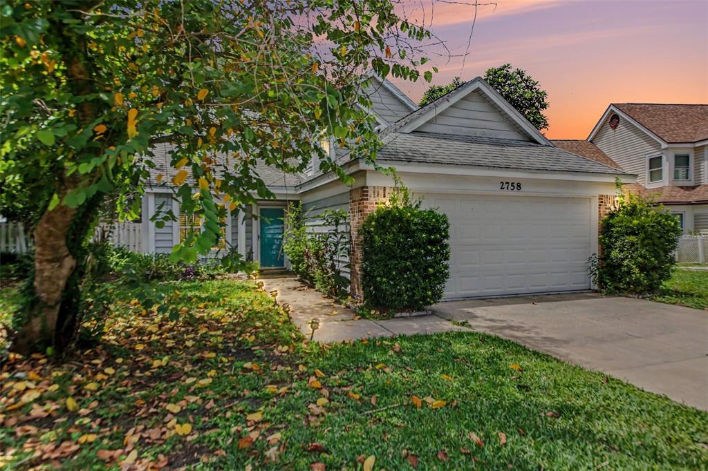 A single-story house with a white garage, teal front door, and a tree-shaded front yard — 2758 WAYMEYER DR, ORLANDO, FL
