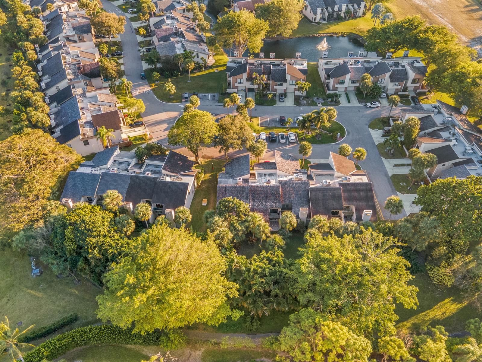 An aerial view shows multiple residential townhome buildings surrounded by lush trees and a pond — 22860 Ironwedge Drive, Boca Raton FL 33433, BOCA RATON, FL