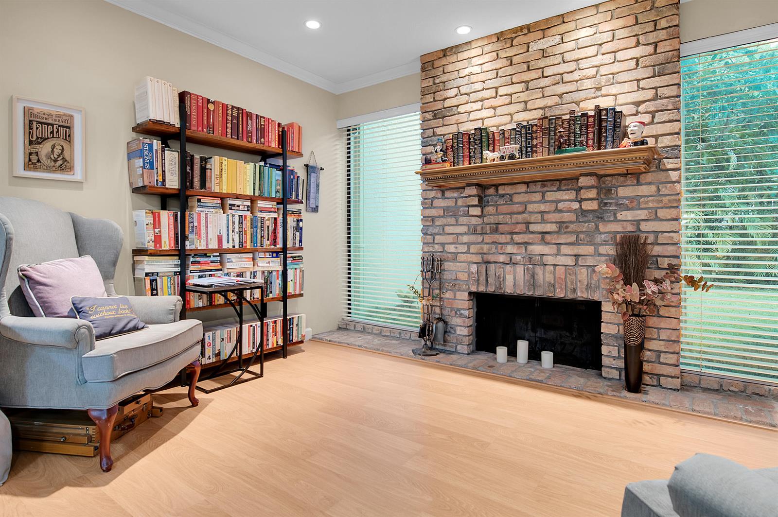 A living room features a brick fireplace, a bookshelf, a grey armchair, and light wood flooring — 22860 Ironwedge Drive, Boca Raton FL 33433, BOCA RATON, FL