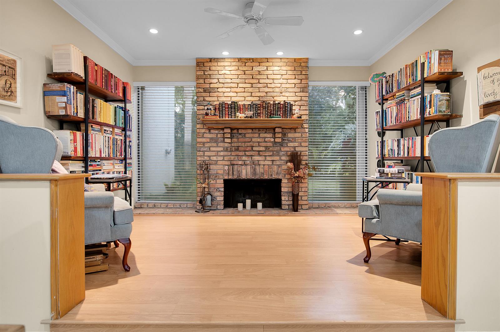 A living room features a brick fireplace, built-in bookshelves, light wood flooring, and two armchairs — 22860 Ironwedge Drive, Boca Raton FL 33433, BOCA RATON, FL