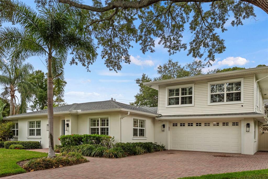 A two-story house with light-colored siding, a brick driveway, and a palm tree in front — 480 W DAVIS BOULEVARD, TAMPA, FL