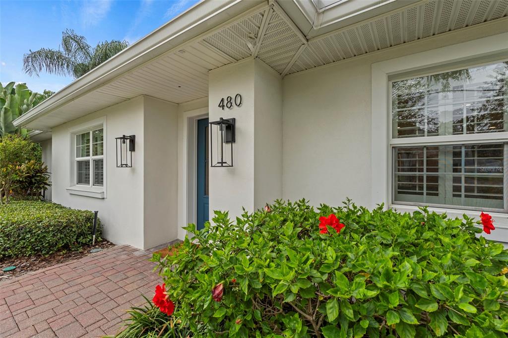 A white house exterior features a blue front door, house number 480, and red flowers — 480 W DAVIS BOULEVARD, TAMPA, FL