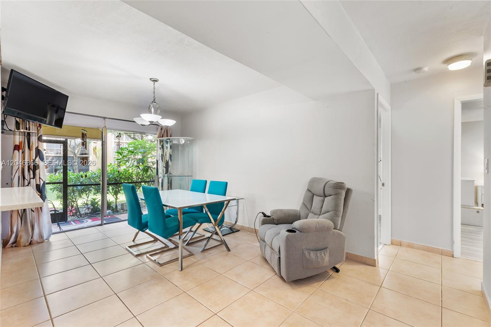 A dining area features a white table, four teal chairs, and a grey recliner — 8401 SW 107th Ave # 144E, Miami FL 33173, MIAMI, FL