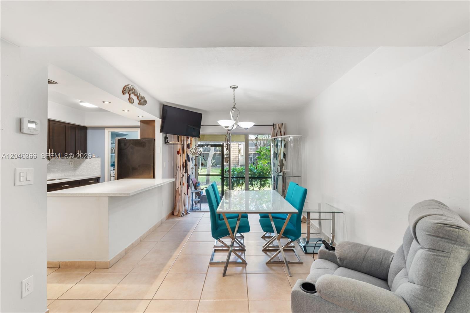 A dining area features a glass table with teal chairs, tile flooring, and an adjacent kitchen — 8401 SW 107th Ave # 144E, Miami FL 33173, MIAMI, FL
