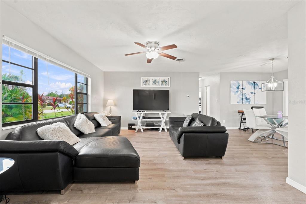 A living room with black leather sofas, wood-look flooring, and an adjacent dining area — 316 GLEN OAK ROAD, VENICE, FL