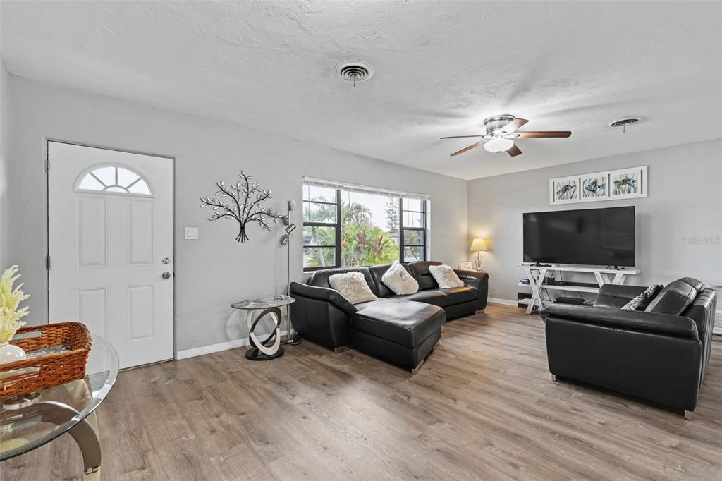 A living room features light gray walls, wood-look flooring, black leather sofas, and a ceiling fan — 316 GLEN OAK ROAD, VENICE, FL