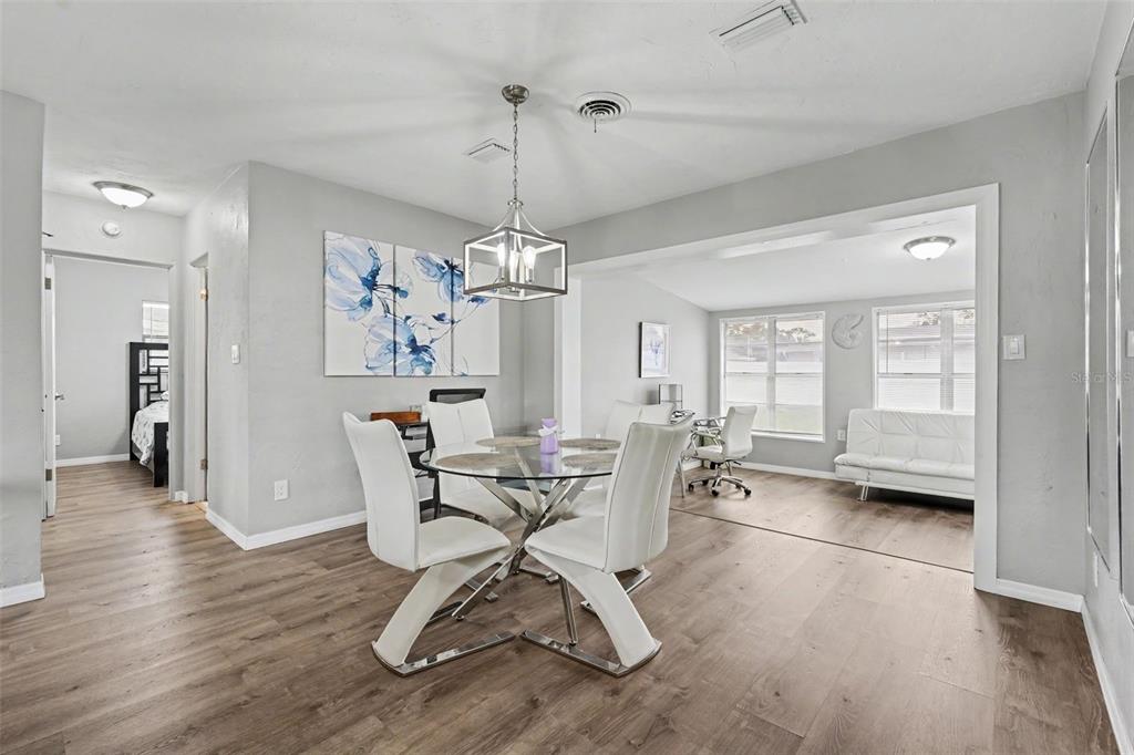 A dining area with a glass table and white chairs opens into a sunlit room — 316 GLEN OAK ROAD, VENICE, FL