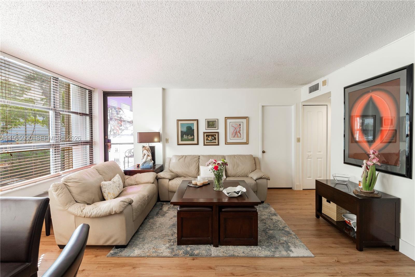 A living room features two beige sofas, a wooden coffee table, and a large framed artwork — 1440 Brickell Bay Dr # 201, Miami FL 33131, MIAMI, FL