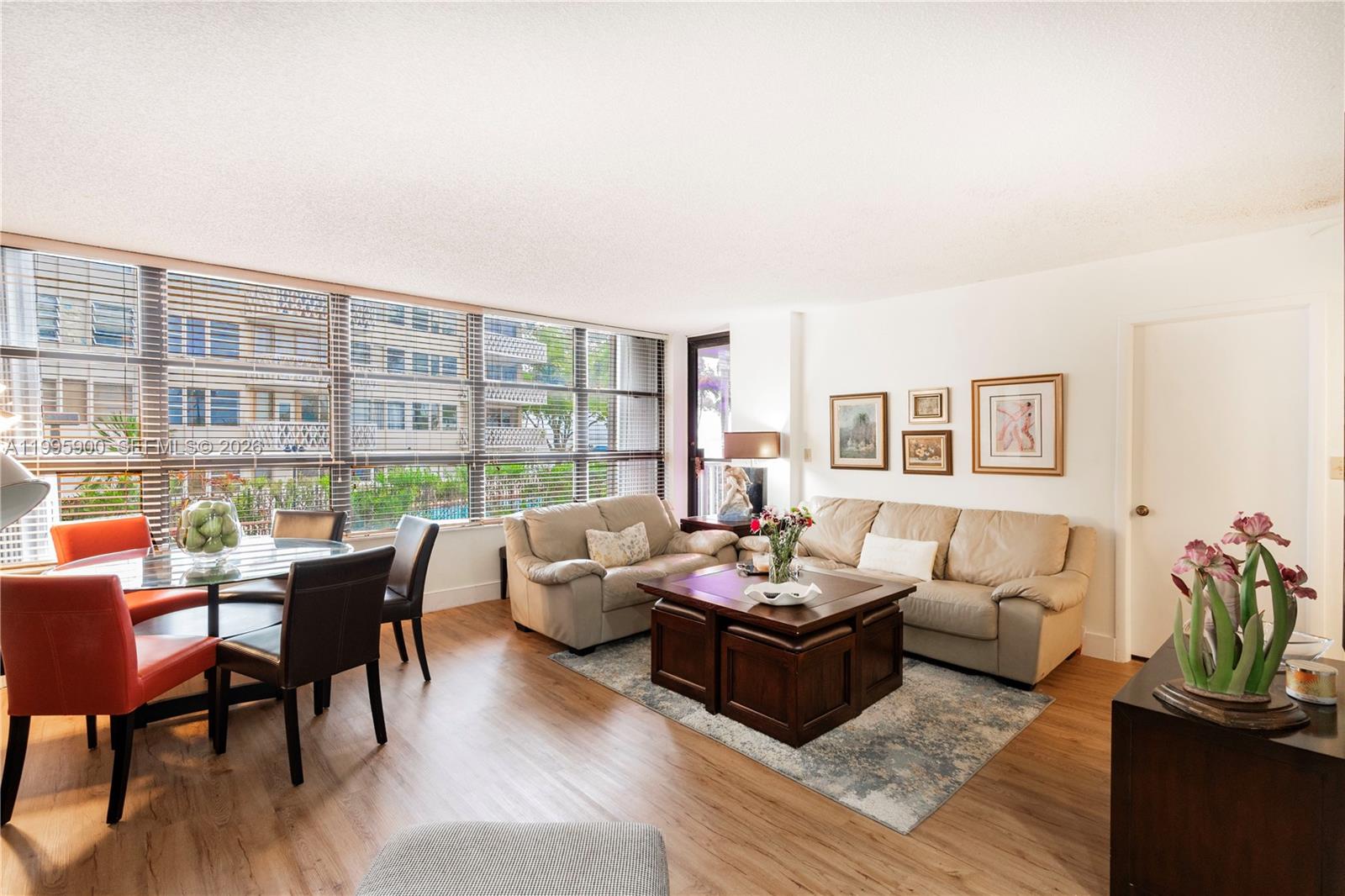 A living and dining room with wood-look flooring, a beige sofa, and large floor-to-ceiling windows — 1440 Brickell Bay Dr # 201, Miami FL 33131, MIAMI, FL