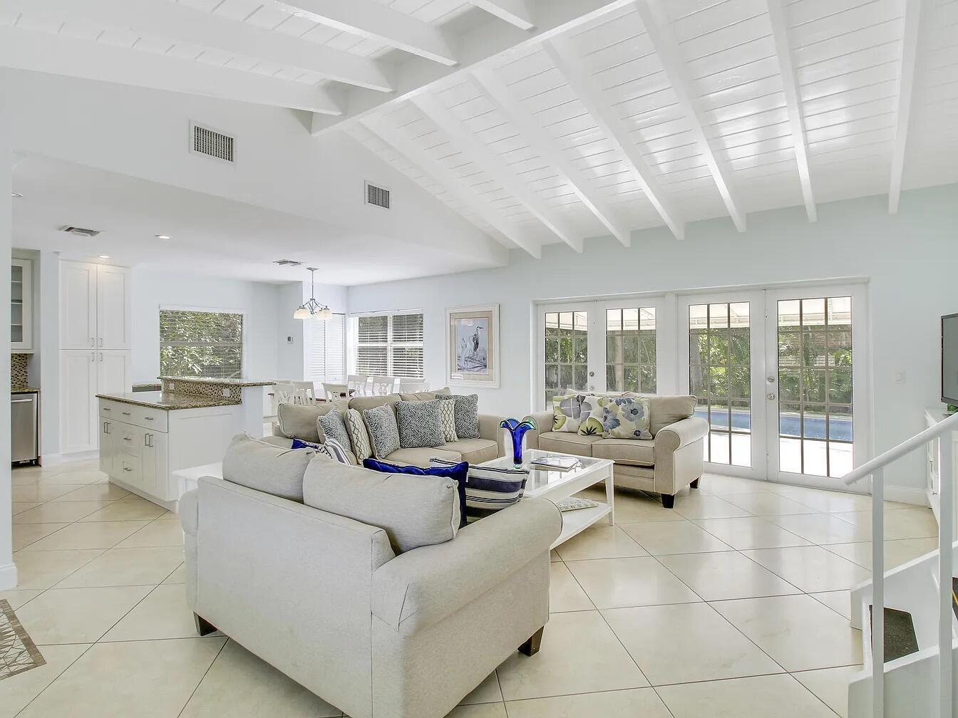 A bright open-concept living room and kitchen with vaulted ceilings and light tile flooring — 1310 Manor Drive, Singer Island FL 33404, SINGER ISLAND, FL