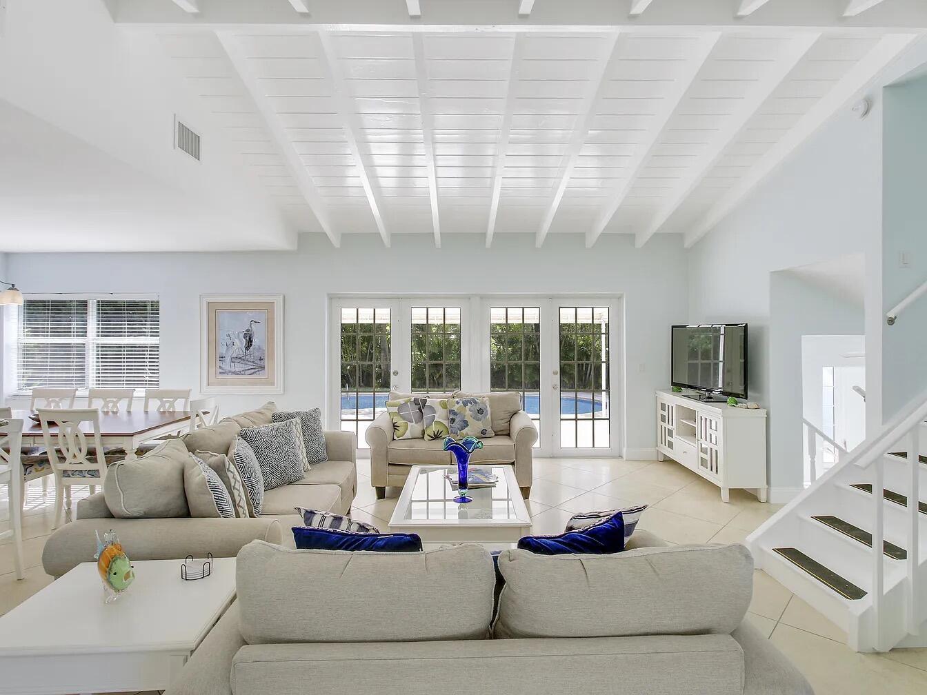 A bright living room features a white vaulted ceiling, tiled floors, and a staircase — 1310 Manor Drive, Singer Island FL 33404, SINGER ISLAND, FL