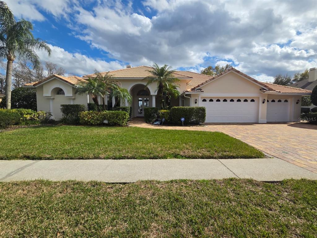 A single-story house with a tile roof, three-car garage, and a landscaped front yard — 3626 SWANS LANDING DRIVE, LAND O LAKES, FL