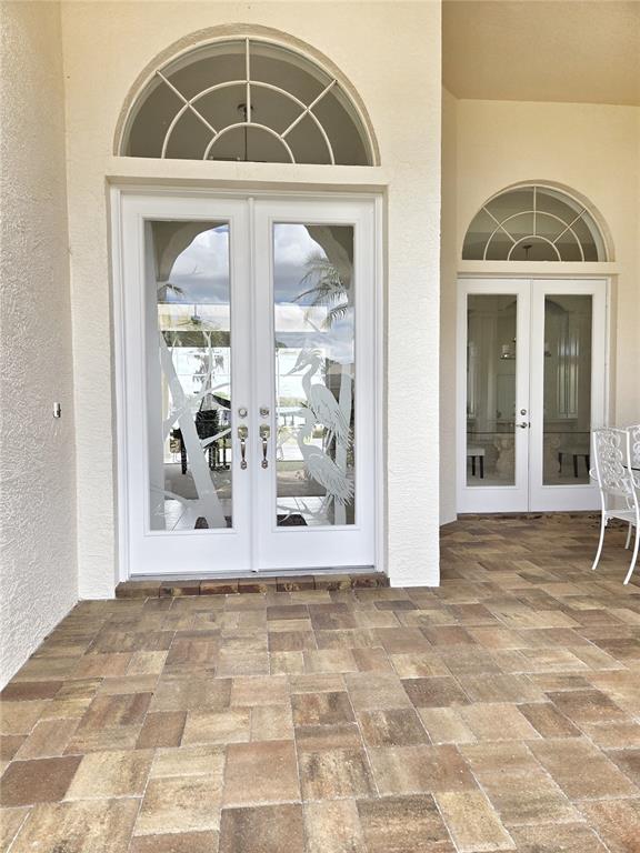 A patio with paver flooring features two sets of white double doors with arched transoms — 3626 SWANS LANDING DRIVE, LAND O LAKES, FL