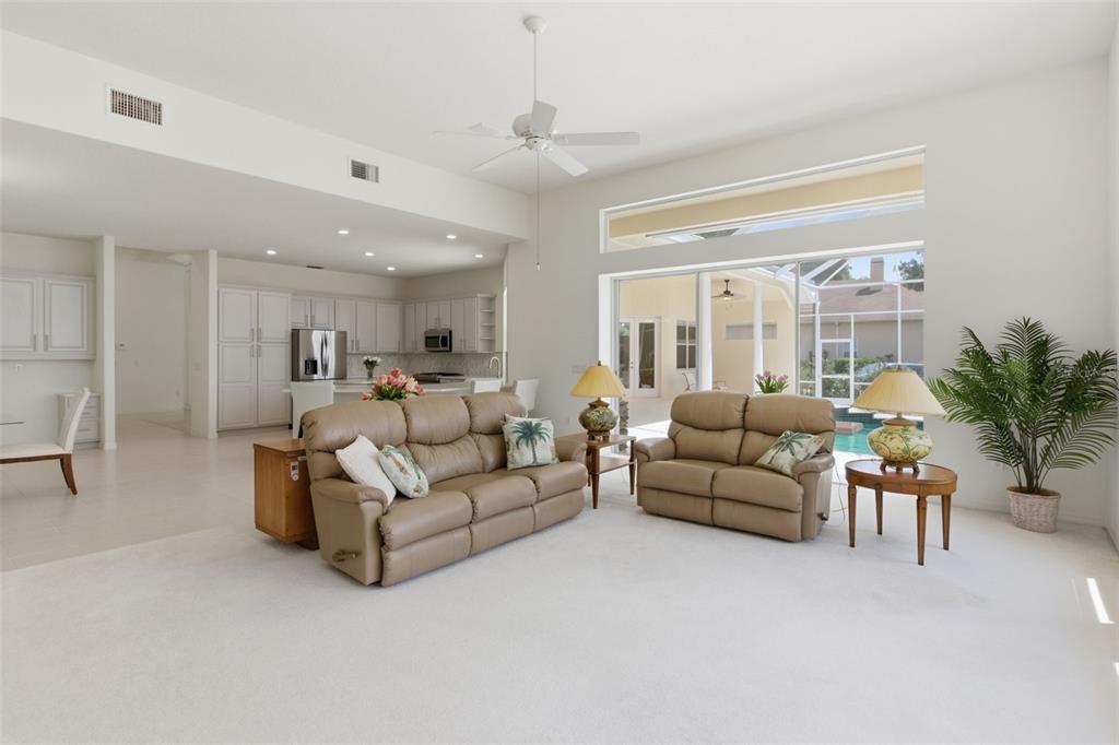 A living room with beige leather sofas, white carpeting, and a view of a pool — 3626 SWANS LANDING DRIVE, LAND O LAKES, FL