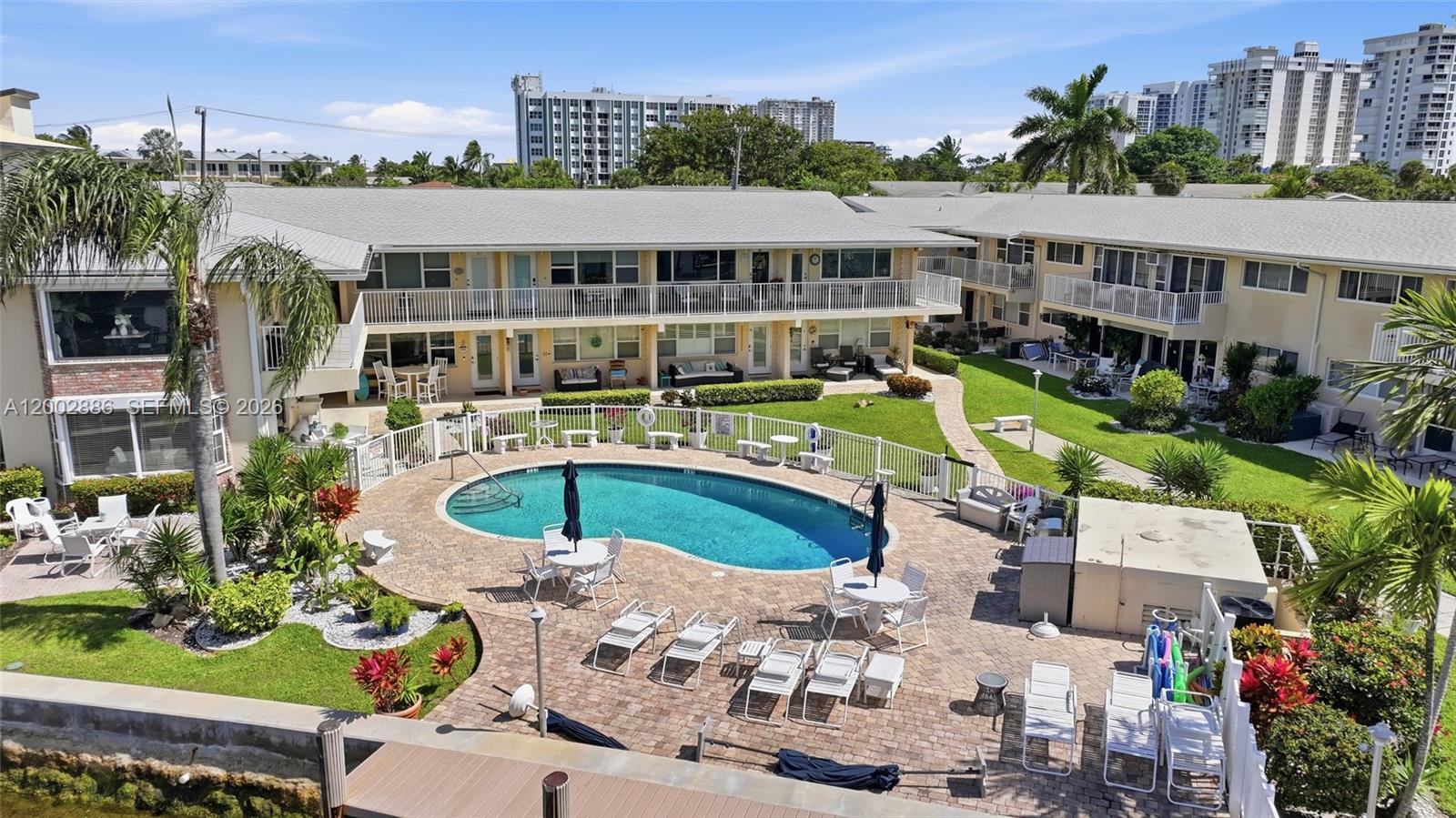 An elevated view of a swimming pool surrounded by a patio and apartment buildings — 3216 SE 12th St # 8, Pompano Beach FL 33062, POMPANO BEACH, FL