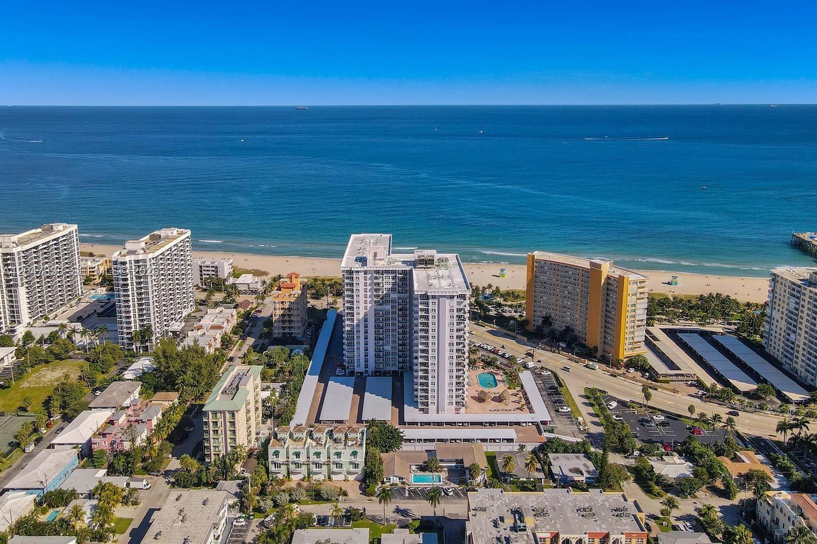An aerial view of a coastal city featuring high-rise apartment buildings near a sandy beach — 405 N Ocean Blvd # 117, Pompano Beach FL 33062, POMPANO BEACH, FL