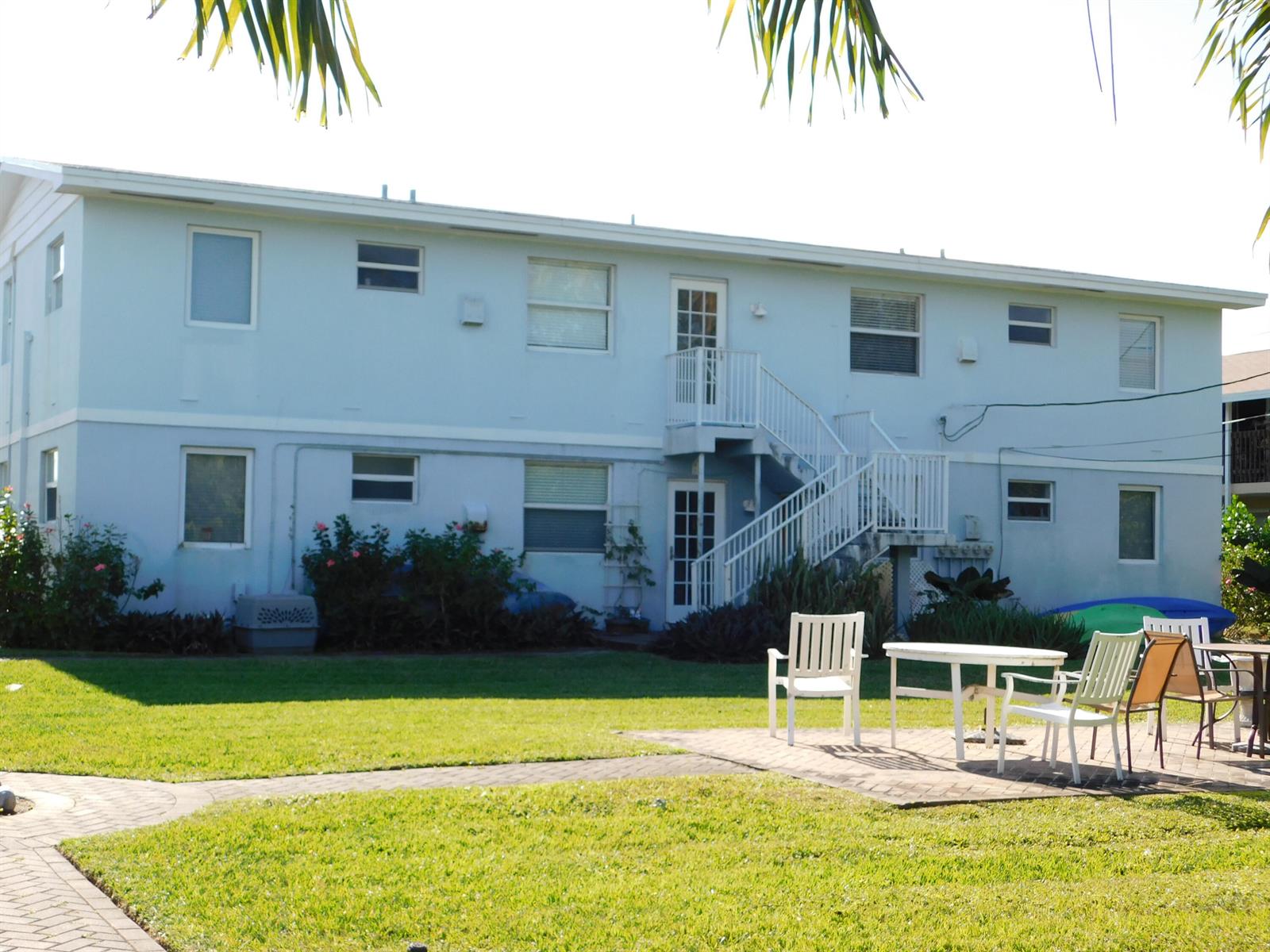 A two-story light blue building with an exterior staircase and a paved patio area — 741 Hummingbird Way # 2, North Palm Beach FL 33408, NORTH PALM BEACH, FL