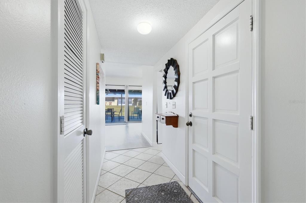 A bright entryway features white walls, tiled floors, a louvered door, and a paneled door — 5887 TIDEWOOD AVENUE UNIT 2, SARASOTA, FL