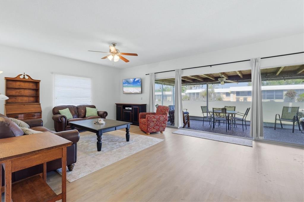 A living room features light wood flooring, leather furniture, and sliding glass doors to a patio — 5887 TIDEWOOD AVENUE UNIT 2, SARASOTA, FL