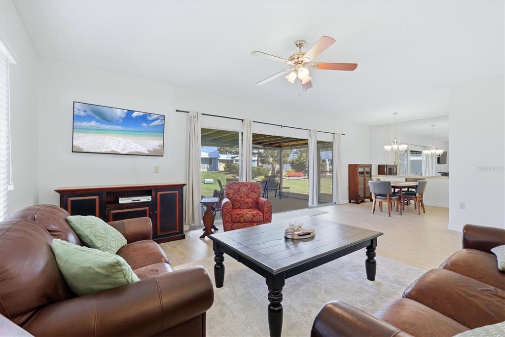 A living room with brown leather sofas, a coffee table, and a view of a patio — 5887 TIDEWOOD AVENUE UNIT 2, SARASOTA, FL