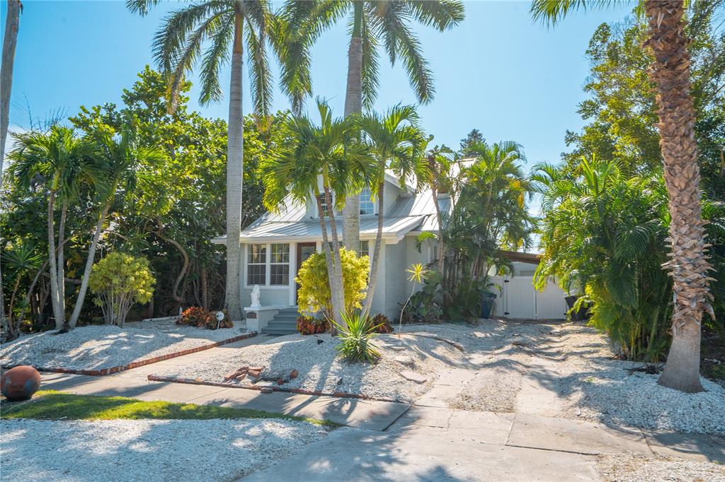 A light-colored house with a metal roof is surrounded by palm trees and gravel landscaping — 3310 E MARITANA DRIVE, ST PETE BEACH, FL