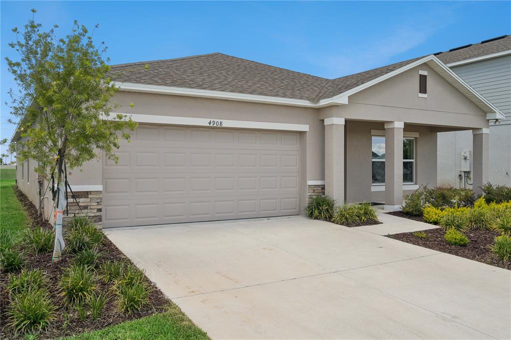 A single-story house with a beige exterior, a two-car garage, and a covered front porch — 4908 BLUEBELL COURT, HAINES CITY, FL