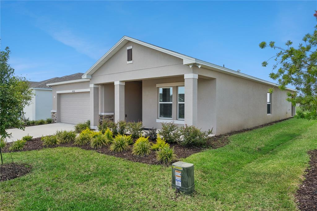 A single-story house with a beige stucco exterior, a two-car garage, and a front lawn — 4908 BLUEBELL COURT, HAINES CITY, FL