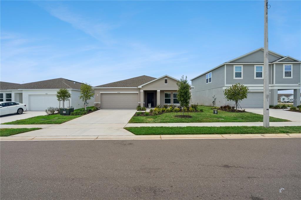 A single-story house with a beige exterior, a two-car garage, and a landscaped front yard — 4908 BLUEBELL COURT, HAINES CITY, FL