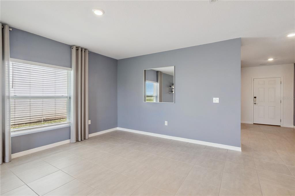 An empty room with gray walls, tile flooring, a window with curtains, and a mirror — 4908 BLUEBELL COURT, HAINES CITY, FL