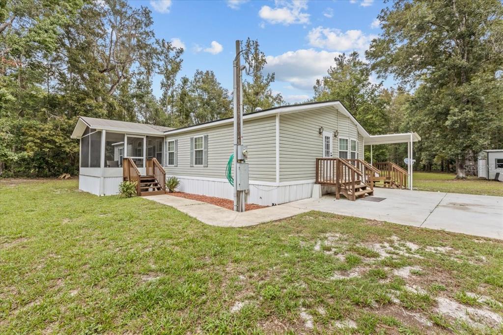 A light green manufactured home with a screened porch, wooden stairs, and a concrete driveway — 1549 NE 642ND STREET, OLD TOWN, FL