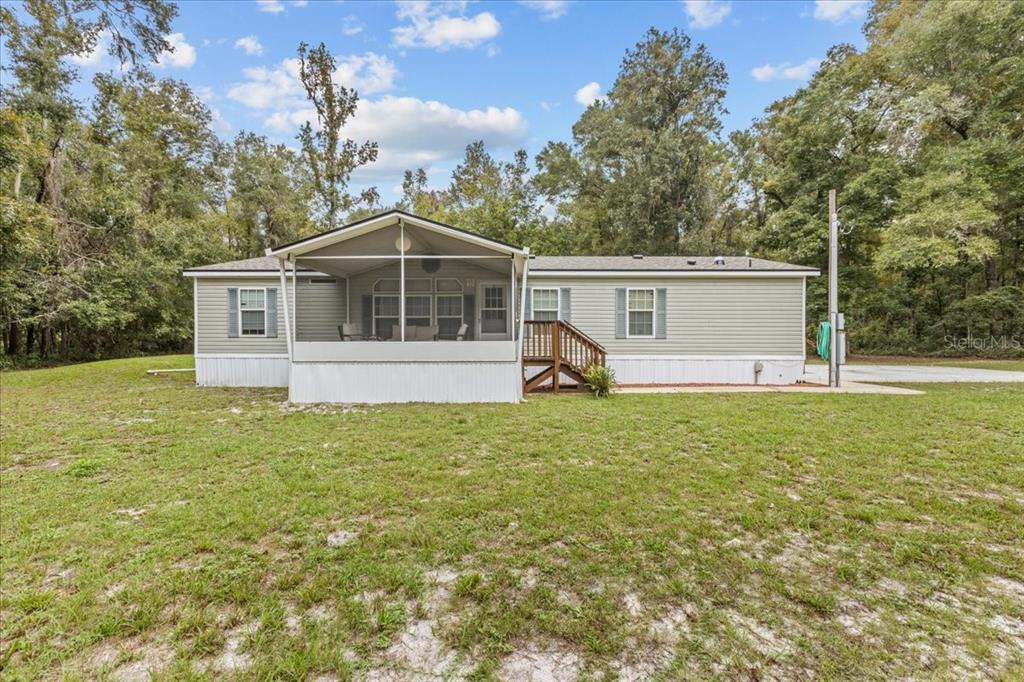 A single-story manufactured home with a screened-in front porch sits on a grassy lot — 1549 NE 642ND STREET, OLD TOWN, FL