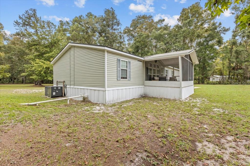 The exterior of a light green manufactured home features a screened-in porch and white skirting — 1549 NE 642ND STREET, OLD TOWN, FL