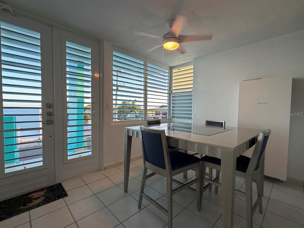 A dining area with a table, chairs, louvered windows, and a view of the water — 471 CALLE 22 BO. MARIANI, MAUNABO, PR