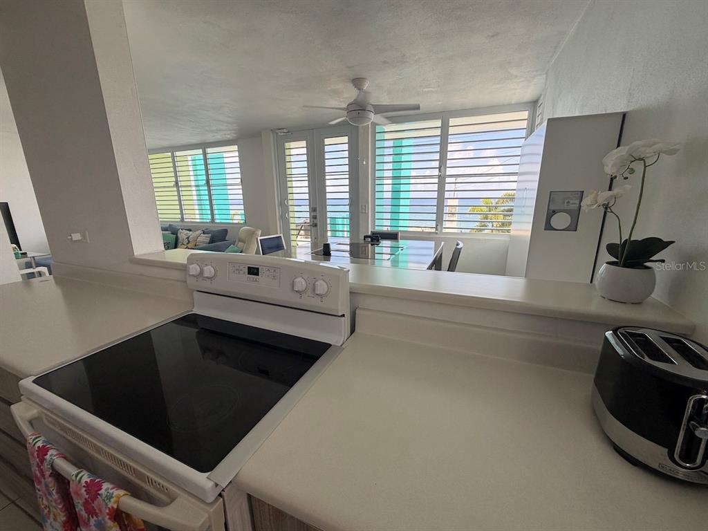 A kitchen with a white electric stove and countertop overlooks a living area with ocean views — 471 CALLE 22 BO. MARIANI, MAUNABO, PR