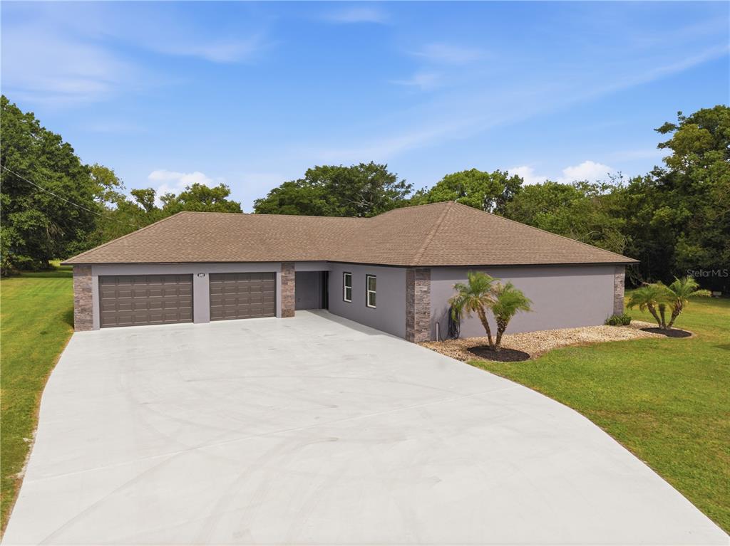 A gray single-story house with a three-car garage and a large concrete driveway — 450 ROSEDALE AVENUE, ST CLOUD, FL