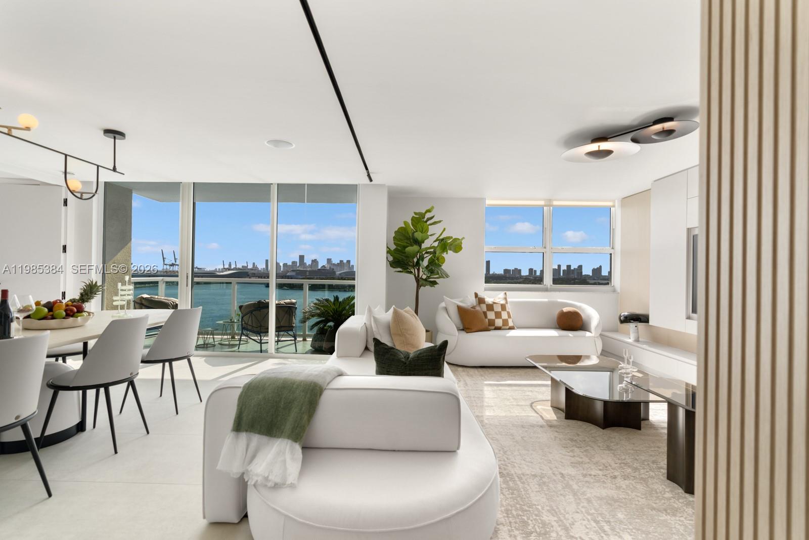 A bright living and dining area features white furniture, modern lighting, and a waterfront balcony view — 650 West Ave, Miami Beach FL 33139, MIAMI BEACH, FL