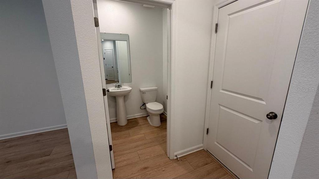 A small bathroom with a pedestal sink and toilet, viewed through an open doorway — 5098 CLAY WHALEY ROAD, ST CLOUD, FL