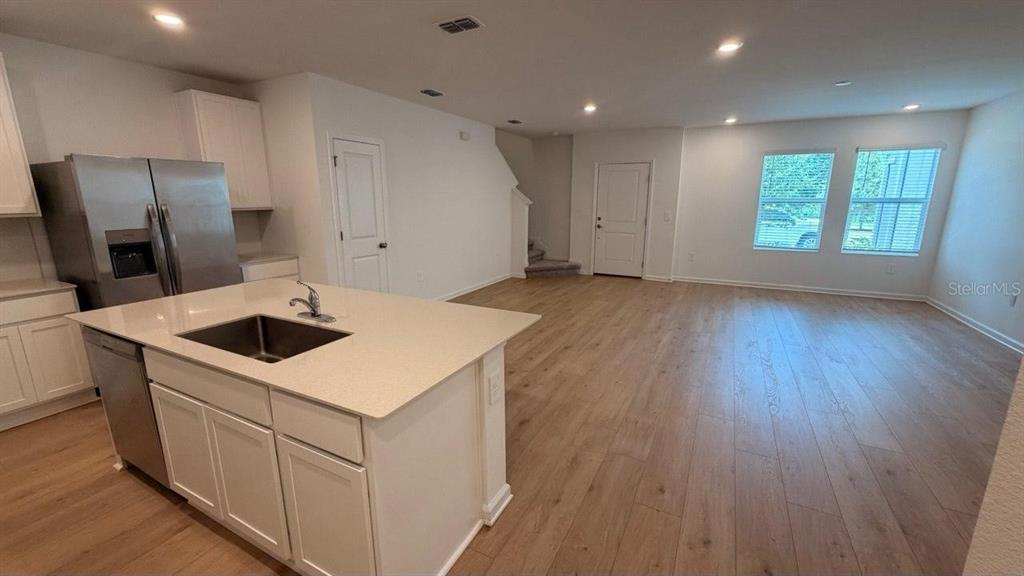 A kitchen with a quartz island and stainless steel appliances opens to a living area — 5098 CLAY WHALEY ROAD, ST CLOUD, FL