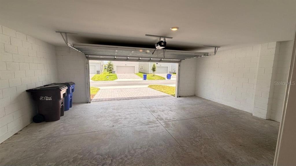 An empty garage with concrete block walls, a concrete floor, and an open overhead door — 5098 CLAY WHALEY ROAD, ST CLOUD, FL