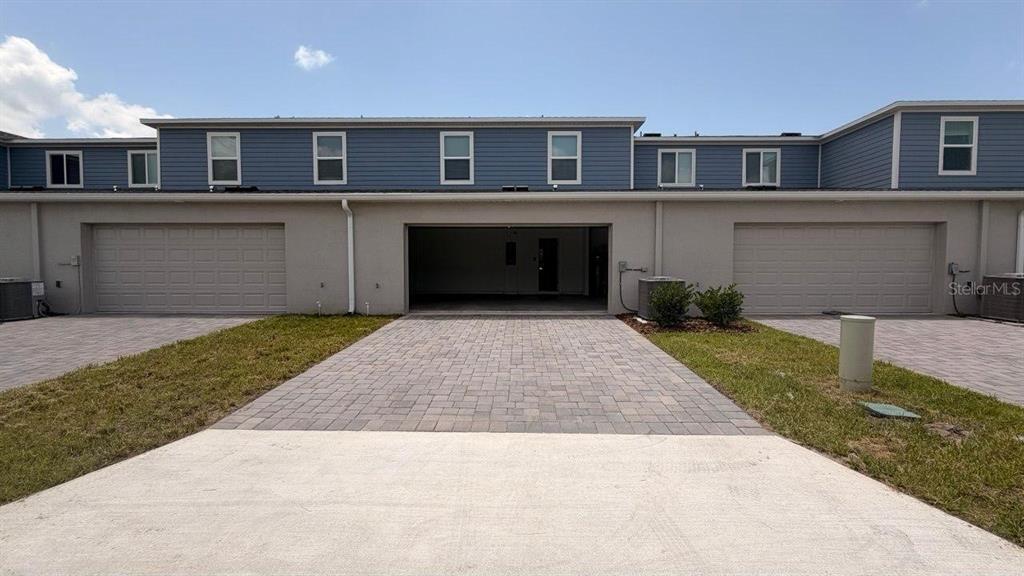 A row of townhouses features three garage bays, two of which are closed — 5098 CLAY WHALEY ROAD, ST CLOUD, FL