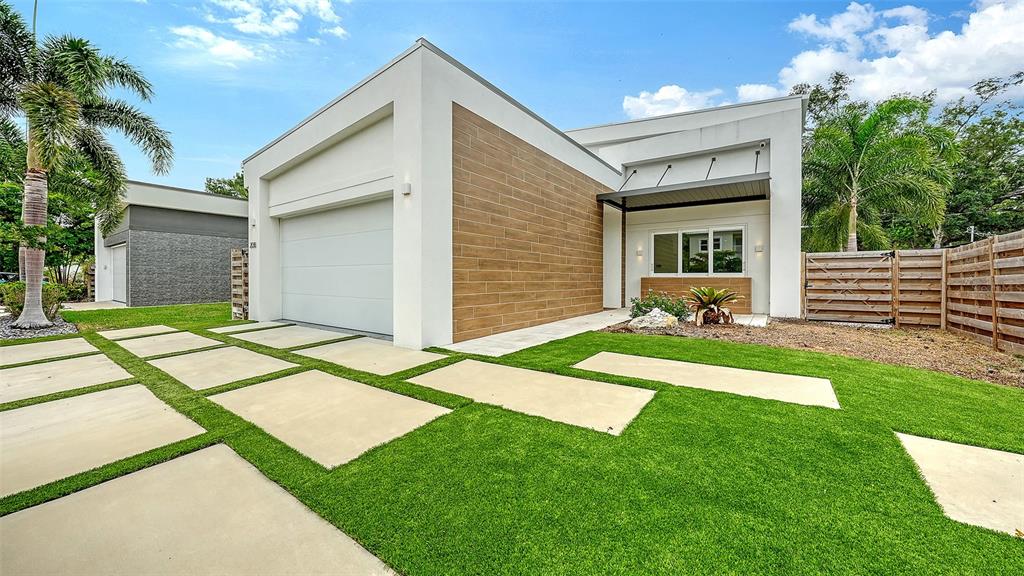 A modern one-story house features a white facade, wood-look siding, and a concrete paver driveway — 2138 HAWTHORNE STREET, SARASOTA, FL
