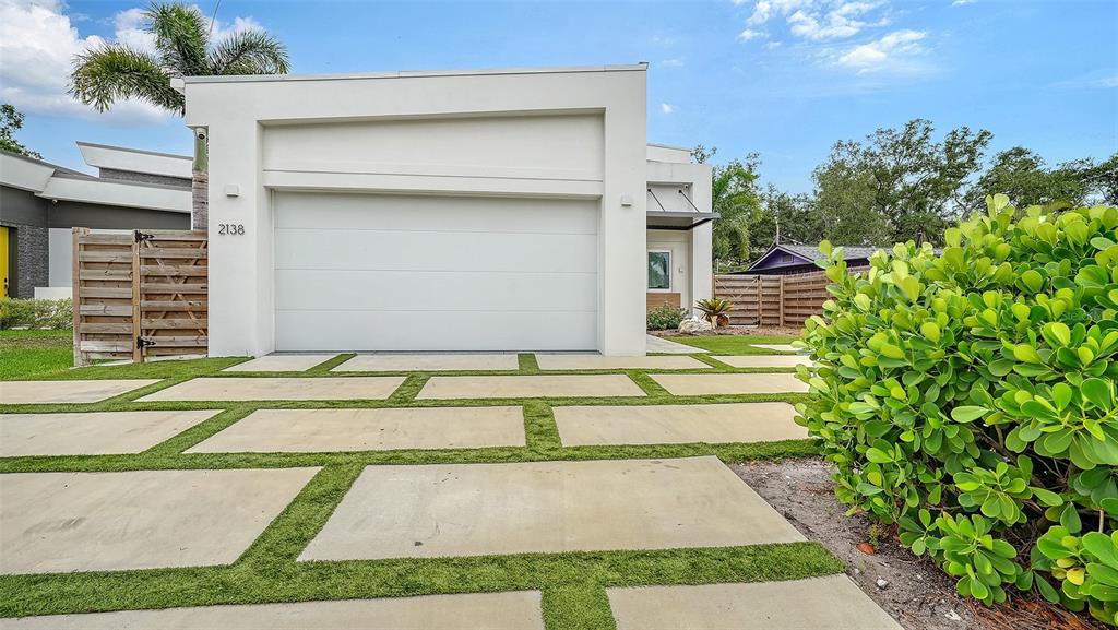 A modern white house features a large garage and a geometric concrete paver driveway — 2138 HAWTHORNE STREET, SARASOTA, FL