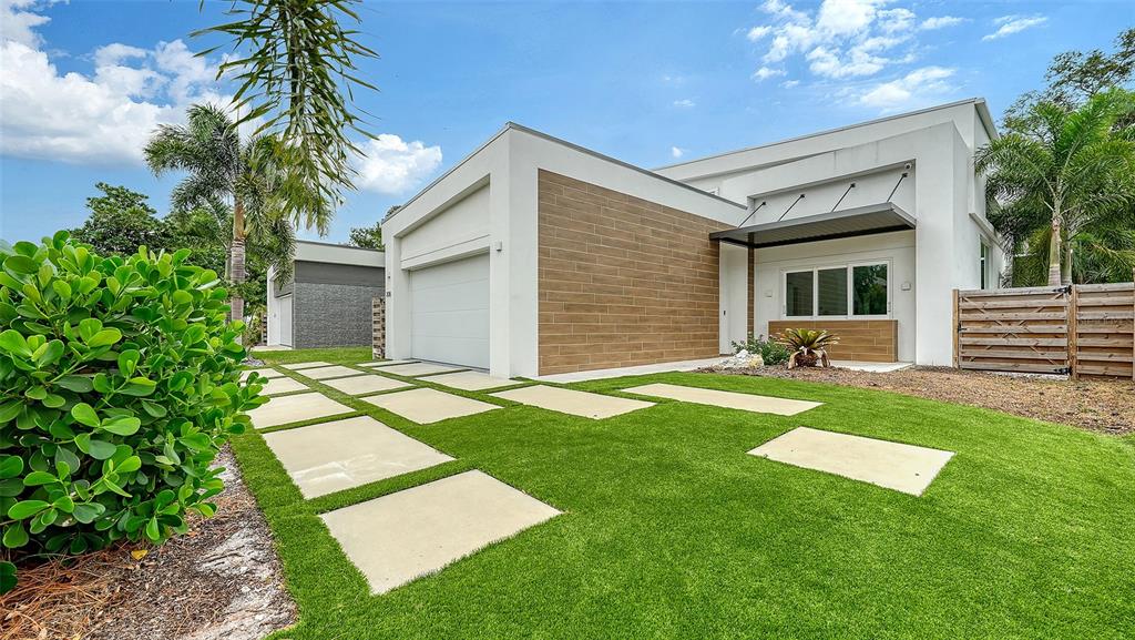 A modern house exterior features a wood-paneled facade, a garage, and a paved driveway — 2138 HAWTHORNE STREET, SARASOTA, FL